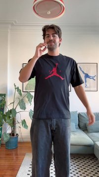 Musta T-paita, jossa on punainen koripalloilijan siluetti ja teksti "A R". Rentoa mallia, lyhyet hihat, yhdistetty tummiin farkkuihin.