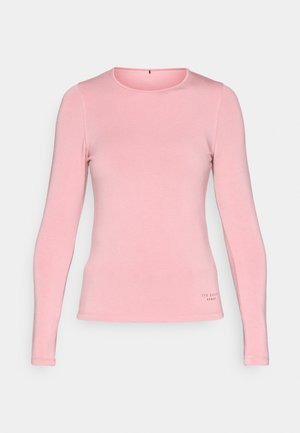 Gaiši rozā garām piedurknēm krekls, izgatavots no mīksta auduma. Iezīmē apaļu kakla izgriezumu un mazu logo akcentu pie apakšmalas. Pieguļošs dizains.