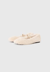 Cream-colored ballet flats made of plush, fuzzy textile with a soft, rounded toe and two elastic straps across the top. Black sole.