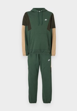 Nike tepláková súprava v zelenej farbe, obsahujúca mikinu s kapucňou s hnedými a pieskovými panelmi, a zodpovedajúce teplákové nohavice s elastickými manžetami a detailom loga.