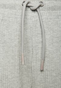 Graue gerippte Sweatpants mit einem Kordelzug und metallicfarbigen Ösen sowie kontrastierenden Enden. Weicher Stoff mit vertikalen Rippdetails.