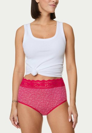 Mutande a vita alta con una fascia di pizzo rosa e tessuto rosa a pois bianchi. Modella che indossa una canotta bianca, con le mani sui fianchi.