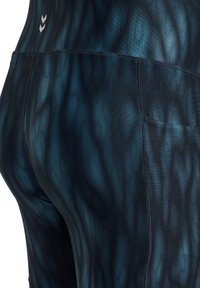 Athletische Shorts mit hohem Bund aus dunkelblauem Stoff mit einem dezenten Wellenmuster. Verfügt über Nahtdetails und ein kleines Logo am Bund.