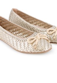 Bailarinas metálicas doradas trenzadas con punta redonda, que cuentan con un lazo de cuerda beige en la parte frontal y un interior suave de un beige claro.