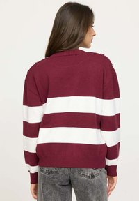 Un pull rayé bordeaux et blanc avec un col rond, des accents texturés sur les épaules et des bords côtes aux poignets et à l'ourlet, fabriqué en matériau tricoté doux.