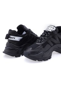 Sneaker neri chunky con parte superiore in mesh e pelle sintetica, dettagli testurizzati e logo sulla linguetta e sul lato. Suola in gomma spessa.