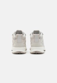 Hellgraue Sportschuhe mit einem strukturierten Mesh-Obermaterial, verstärktem Absatz und einer gemusterten Gummisohle. Verfügt über dezente Branding-Details.