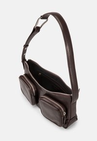 Tmavě hnědá kožená kabelka přes rameno se dvěma předními kapsami na zip a otevřeným hlavním oddělením, zobrazená z bočního úhlu.