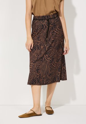 Jupe midi à motifs marron avec taille à cordon, présentant des motifs en zigzag semblables à ceux des zèbres dans des teintes plus foncées sur un tissu léger.
