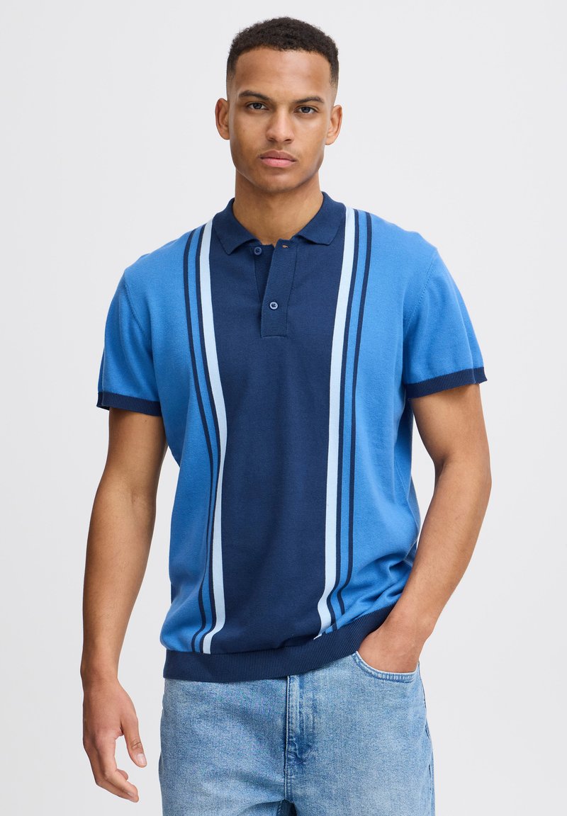 Kötött pólóing, kék és sötétkék színösszeállítással, függőleges csíkokkal és kétgombos kigombolóval. Rövid ujjak, bordázott mandzsettával.