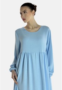 Jasnoniebieska sukienka z długim rękawem i okrągłym dekoltem, o fakturowanej tkaninie, z marszczonym wcięciem w talii i luźnym kroju, prezentująca komfortowy design.