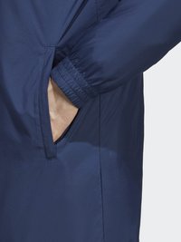 Námořnická modrá bunda s hladkým, vodotěsným povrchem, elastickými manžetami a boční kapsou s elegantním, minimalistickým designem.