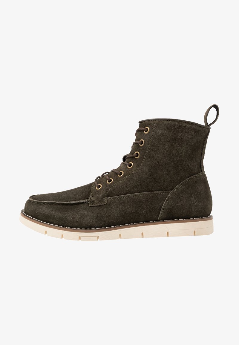 Stivaletto alla caviglia in suede verde scuro con sei occhielli metallici, suola in gomma beige chiaro e un linguetta posteriore per una facile calzata. Texture liscia.