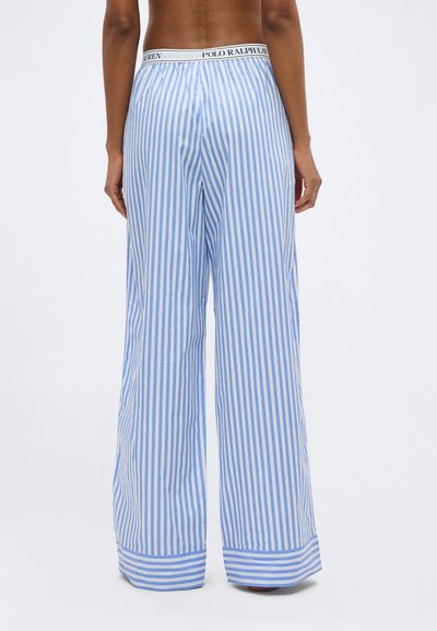 Άτομο που φορά φαρδιά, μπλε και λευκή κάθετη ριγέ παντελόνια με ελαστική μέση "Polo Ralph Lauren", εμφανιζόμενο από πίσω με φόντο λευκό.