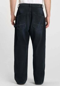 Donkerblauwe denim broek met een relaxte pasvorm, voorzien van twee achterzakken, een riemlus en een zichtbare taillebanddetail.