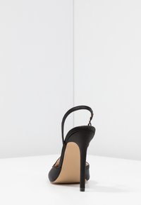Svart satin högklackad slingback-sko med spetsig tå, justerbar ankelsnodd och en slät yta. Stiletto-häl design.