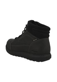 Botte de cheville en cuir noir avec un dessus texturé, un bout rond et un col rembourré. Comprend des coutures contrastées et une semelle en caoutchouc.