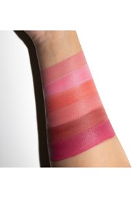 Muestras de varios tonos de rosa y rojo aplicados sobre la piel, mostrando diferentes texturas y acabados en franjas horizontales en el brazo.