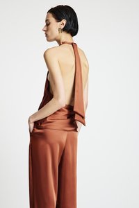 Vue arrière d'une combinaison sans manches en satin marron avec un col halter et un dos décolleté, dotée de poches et d'une texture lisse et brillante.