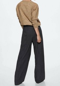 Pull en maille couleur fauve à coupe ample, associé à un pantalon charcoal taille haute à jambes larges. Le tissu semble doux avec une texture lisse.