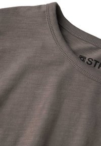 Grå kortärmad skjorta med rund hals, slät textur och subtilt horisontellt mönster. Märkesetikett synlig nära halsringningen.