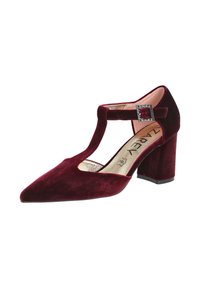 Tacones T-strap de terciopelo burdeos con puntera afilada, que presentan un acento de hebilla cuadrada texturizada y un tacón cuadrado. Forro interior dorado.