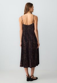 Schwarzes und braunes Tierdruckkleid mit dünnen Trägern, fließendem Design und Midi-Länge. Glattes Gewebe mit plissierter Textur.