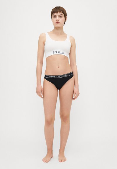 Bela bombažna bralette s tekstom "POLO" in črne bikini hlačke z raztegnjenim pasom "POLO RALPH LAUREN", oboje preprosto in prilegajoče s minimalističnim dizajnom.