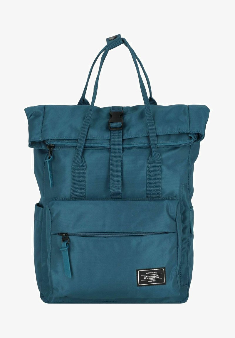 Zaino color teal con design a roll-top, realizzato in tessuto resistente. Presenta un compartimento principale con zip e una tasca frontale con zip. Include spallacci regolabili.