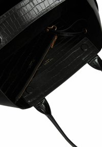 Sac en cuir noir avec texture crocodile, accents lisses, une poche zippée et une poche interne avec quincaillerie dorée.