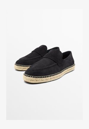 Sorte loafers i ruskind med beige jute-såler i espadrille-stil vist på en hvid baggrund, vinklet for at vise deres profil og overdel.