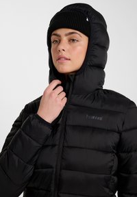 Czarna kurtka puchowa z wysokim kołnierzem i kapturem, o pikowanej teksturze i zamkiem błyskawicznym z przodu. Logo marki jest dyskretnie umieszczone.