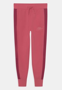 Růžové tepláky s tmavšími růžovými bočními panely, elastickým pasem se stahovací šňůrkou a jemným logem Nike na přední straně.