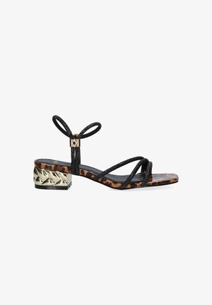 Sandalia negra de tiras con suela de estampado de leopardo y tacón bajo de bloque texturizado metalizado en oro, con lazo en el tobillo y diseño de puntera abierta.