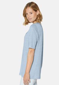 Lichtblauw T-shirt met korte mouwen van zachte stof. Ontspannen pasvorm met een ronde hals en subtiele textuurdetails op de achterkant.