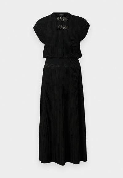 Black pleated dress with short sleeves, featuring a round neckline and decorative accents at the chest. Soft, textured fabric.