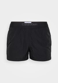 Pantaloni da bagno neri con una cintura elastica che presenta il logo "Calvin Klein". Realizzati in materiale leggero e liscio con una vestibilità ampia.