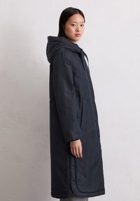 Langer navyfarbener Parka mit Kapuze, ausgestattet mit einem Reißverschluss vorne, seitlichen Taschen und Knopfdetails am Saum. Glattes, leichtes Material.