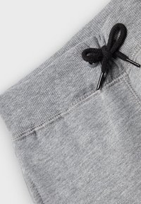 Grau Sweatpants mit einem gerippten Bund, ausgestattet mit einem schwarzen Kordelzug mit Kunststoffspitzen. Der Stoff wirkt weich mit einer glatten Textur.