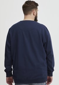 Sweatshirt a maniche lunghe blu navy con scollatura a girocollo. Tessuto morbido, con polsini a costine e orlo dritto, dettagli delle cuciture minimi.