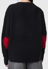 Czarny sweter z dzianiny o fakturowanym wykończeniu, z czerwonymi wzorami serc na każdym rękawie oraz ściągaczem u dołu.