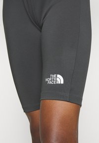 The North Face musta aktiivisortsid mustas värvitoonis, mis on lähedalt istuvad, sileda tekstuuriga ja valge logo detailiga vasakus alumises jalas.