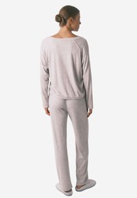 Lys grå loungewear-sæt med lange ærmer og brede bukser. Blød ribbet tekstur med en afslappet pasform, der har en rund halsudskæring.