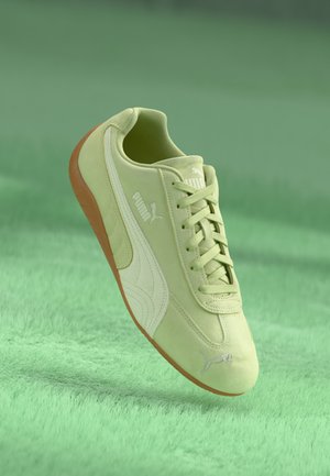 Lime green suede sneaker with white accents, rounded toe, and orange rubber sole. Features a logo on the side and flat laces.