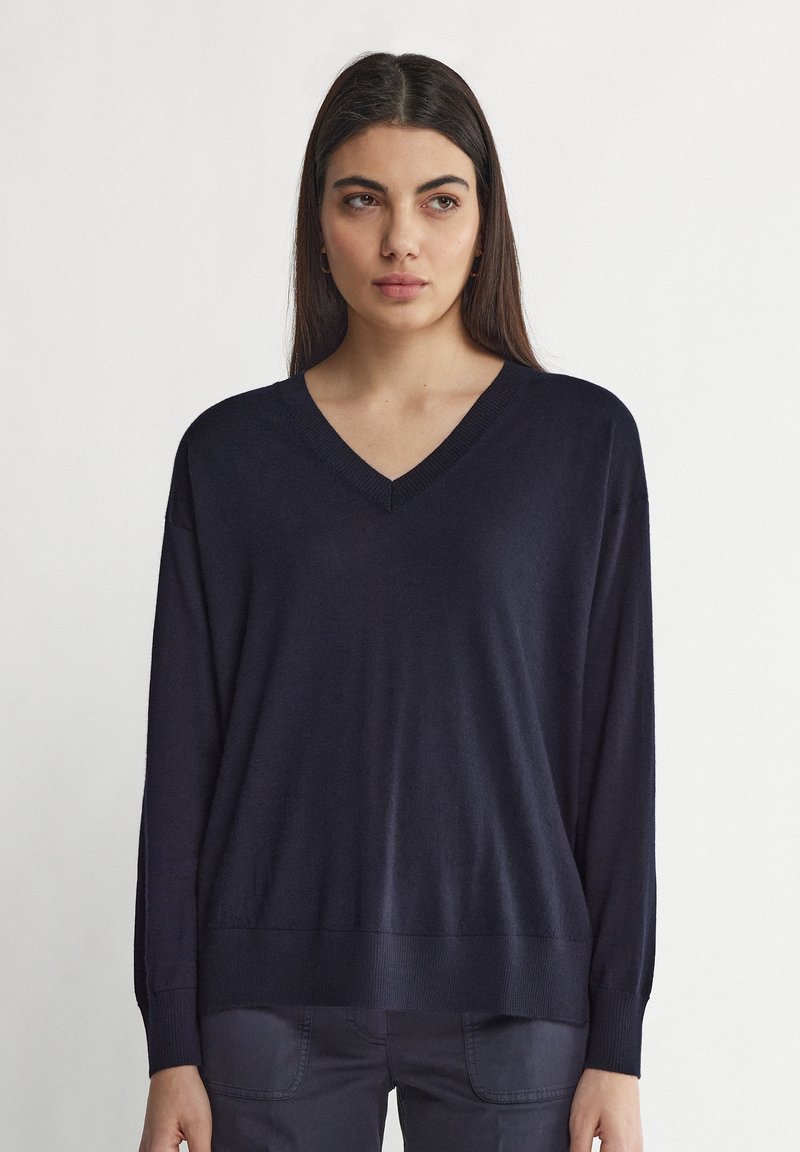 Marinblå V-halströja i mjukt, stickat tyg med långa ärmar och ribbade muddar och nederkant, med en avslappnad passform och minimala designdetaljer.