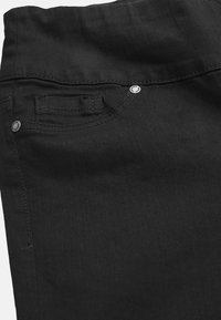 Svarta denim-jeans med en slät textur, klassisk femficksdesign och silverdetaljer på knappen och nitarna.