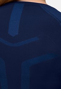 Granatowy sportowy top z teksturowanymi niebieskimi akcentami i geometrycznymi wzorami. Tkanina wydaje się gładka i dopasowana, podkreślając kontury pleców.