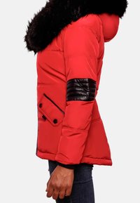 Rød pusterjakke med en sort faux fur hætte, sidelomme med knaplukning og sort læderdetalje på ærmet. Struktureret og quiltet design.