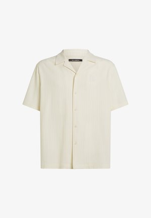 Rövid ujjú, világos bézs színű gombos ing finom, texturált csíkos mintával. Klasszikus gallérral és normál szabással rendelkezik.