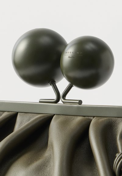 Χειροποίητη δερμάτινη τσάντα χειρός σε ελιά πράσινη απόχρωση με υφή πτυχώματος, διαθέτοντας δύο σφαιρικά στοιχεία στην κορυφή και ένα περιμετρικό μεταλλικό πλαίσιο που ταιριάζει στο χρώμα.